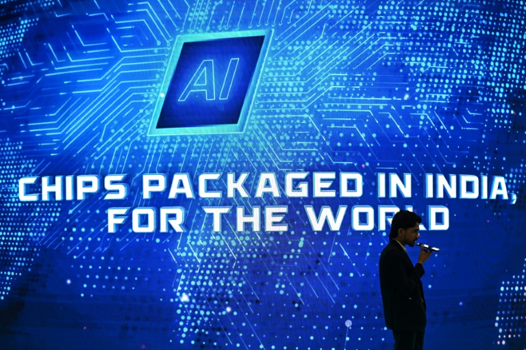 Un visiteur utilise son téléphone portable alors qu'il passe devant un stand lors du sommet mondial sur l'intelligence artificielle à New Delhi, le 17 février 2026