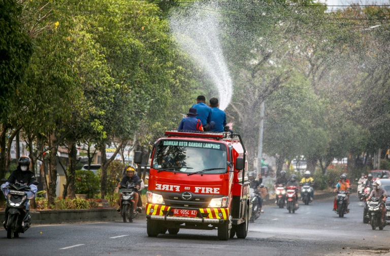 Des pompiers projettent de l'eau dans une rue pour évacuer les cendres provoquées par l'éruption du volcan Anak Krakatoa à Bandar Lampung, le 6 septembre 2026 en Indonésie