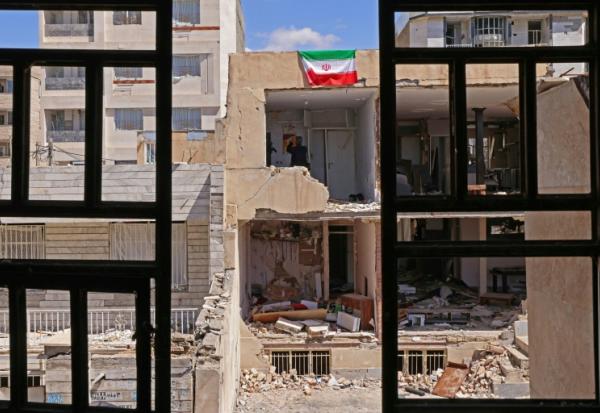 Un drapeau iranien sur le pan de mur d'un immeuble résidentiel endommagé par de récentes frappes à Karaj, au sud-ouest de Téhéran, le 3 avril 2026 