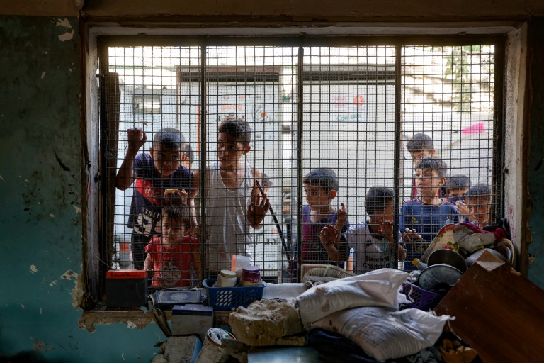 Des enfants palestiniens regardent depuis le grillage d'une salle de classe endommagée de l'école al-Farabi transformée en abri pour déplacés, après avoir été touchée par une frappe israélienne dans la ville de Gaza, le 7 septembre 2025