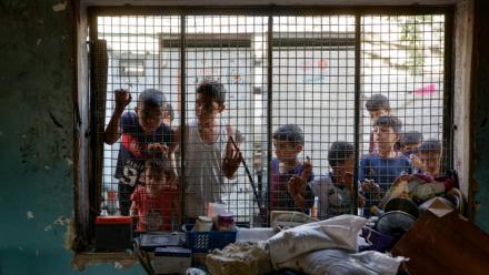 Des enfants palestiniens regardent depuis le grillage d'une salle de classe endommagée de l'école al-Farabi transformée en abri pour déplacés, après avoir été touchée par une frappe israélienne dans la ville de Gaza, le 7 septembre 2025