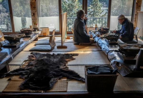 Des clients déjeunent près d'une fourrure d'ours dans un restaurant qui sert de la viande de plantigrade, le 12 décembre 2025 à Chichibu, dans la préfecture de Saitama, au Japon