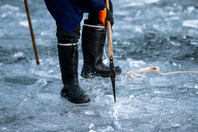 Un fidèle du culte shinto brise de la glace avec une hache sur le lac Suwa, le 29 janvier 2026 dans la préfecture de Nagano, dans le centre du Japon 