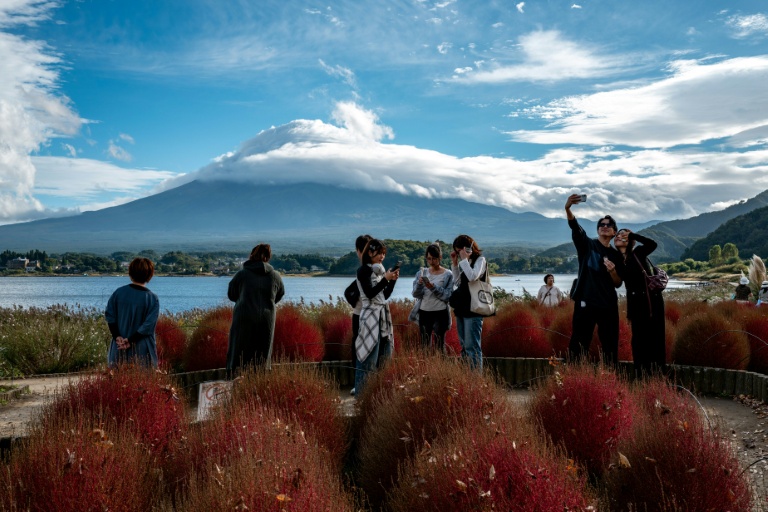 Des touristes prennent des photos devant le Mont Fuji, le 18 octobre 2025 à Fujikawaguchiko, au Japon