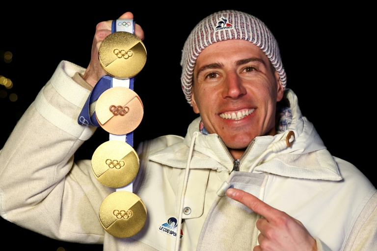 Quentin Fillon Maillet pose avec ses quatre médailles, trois d'or et une d'argent, gagnées aux JO de Milan Cortina.