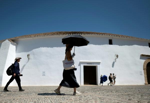 Une femme portant des gants et un chapeau s'abrite du soleil avec un parapluie à Ronda, dans le sud de l'Espagne, le 2 juillet 2025 