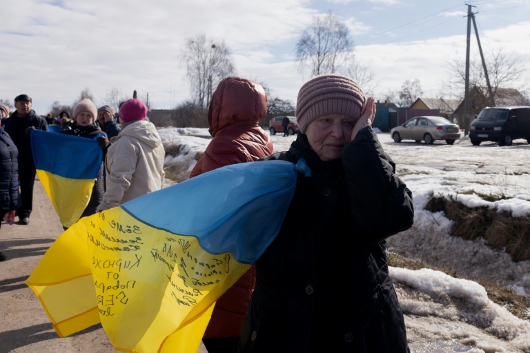 Une femme en larmes sur le bord de la route au  passage d'un convoi de soldats ukrainiens libérés par les Russes après un échange de prisonniers, le 6 mars 2026 dans un lieu non précisé dans le nord de l'Ukraine