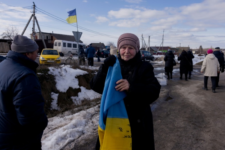 Une femme tient un drapeau ukrainien pour accueillir un convoi de soldats libérés par les Russes après un échange de prisonniers, le 6 mars 2026 dans un lieu non précisé dans le nord de l'Ukraine