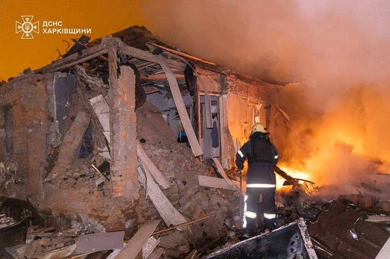 Photo diffusée le 26 février 2026 par le Service ukrainien des situations d'urgence montrant un pompier éteignant un incendie dans une maison endommagée après une attaque russe à Kharkiv