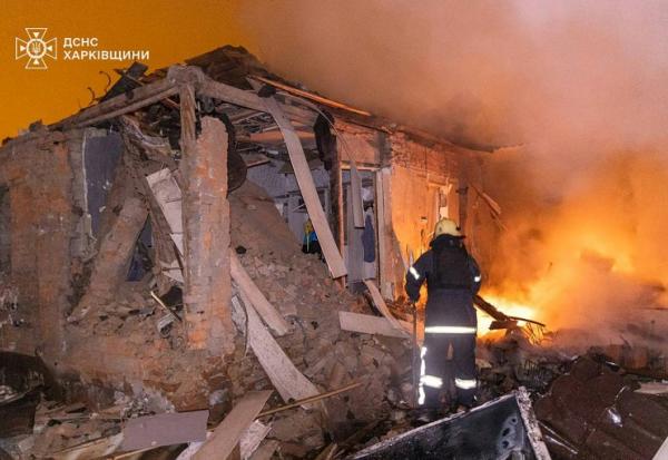 Photo diffusée le 26 février 2026 par le Service ukrainien des situations d'urgence montrant un pompier éteignant un incendie dans une maison endommagée après une attaque russe à Kharkiv