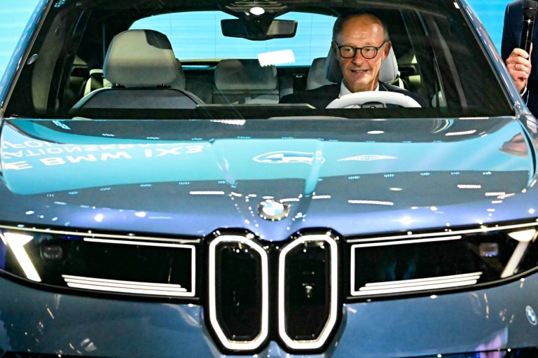 Le chancelier allemand Friedrich Merz assis dans une BMW IX3 sur le stand du constructeur automobile lors de l'ouverture du Salon international de l'automobile IAA, le 9 septembre 2025 à Munich, dans le sud de l'Allemagne