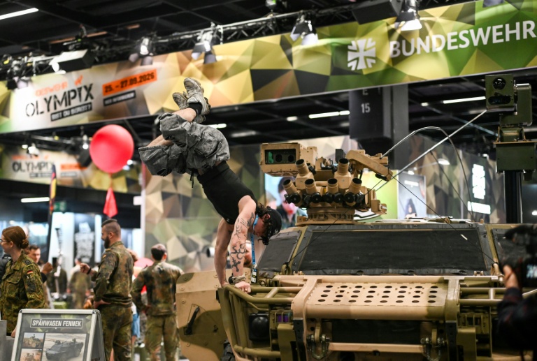 Un visiteur fait le poirier sur un véhicule de l'armée allemande, sur le stand de la Bundeswehr, au plus grand salon mondial du fitness, la Fibo, à Cologne (ouest de l'Allemagne), le 16 avril 