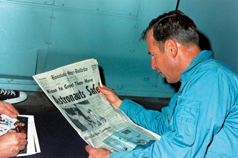 Jim Lovell en train de lire le journal évoquant le sauvetage périlleux d'Apollo 13 le 17 avril 1970, à bord de l'USS Iwo