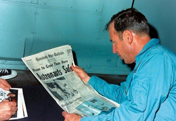 Jim Lovell en train de lire le journal évoquant le sauvetage périlleux d'Apollo 13 le 17 avril 1970, à bord de l'USS Iwo