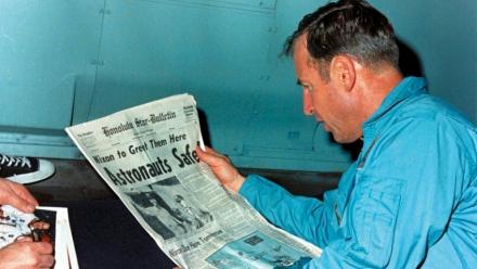 Jim Lovell en train de lire le journal évoquant le sauvetage périlleux d'Apollo 13 le 17 avril 1970, à bord de l'USS Iwo