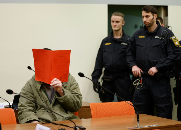 L'Afghan Farhad N. (g.), le visage caché derrière un dossier, est assis dans la salle d'audience du tribunal, le 16 janvier 2026 à Munich, pour le début de son procès pour avoir foncé en voiture dans la foule à Munich en 2025