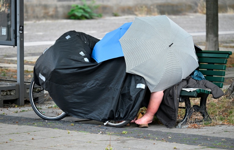 Un Sdf sur un banc public abrité sous des parapluies à Berlin le 28 juin 2026
