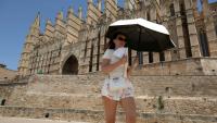 Une touriste se protège du soleil avec une ombrelle pendant qu'elle visite la cathédrale de Palma de Majorque, le 20 juin 2026 aux îles Baléares, en Espagne