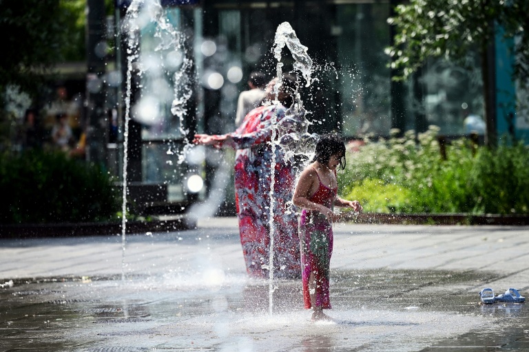 Une enfant se rafraîchit sous un jet d'eau dans un parc à Bruxelles, le 19 juin 2026