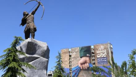 Une sculpture d'Arash l'Archer, figure légendaire de la mythologie persane, et une affiche géante représentant le détroit d'Ormuz avec l'inscription "À jamais dans la main de l'Iran", place Vanak à Téhéran, le 25 mai 2026