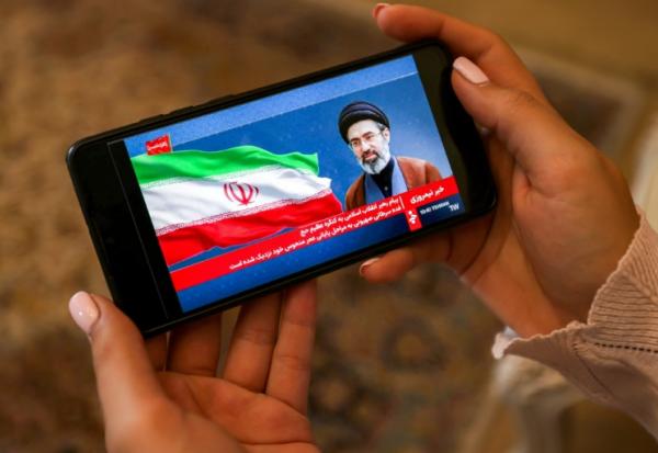 Une femme consulte sur son mobile un message du guide suprême iranien Mojtaba Khamenei, le 26 mai 2026 à Téhéran