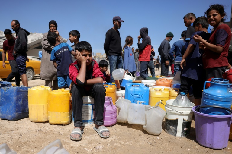 Des Palestiniens attendent de pouvoir obtenir de l'eau dans un camp de personnes déplacées à Gaza-Ville, le 20 mai 2025, sur fond de guerre entre Israël et le mouvement palestinien Hamas
