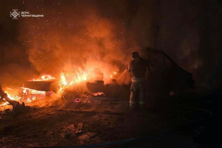 Photo prise et diffusée par les services d'urgence ukrainiens, le 23 décembre 2025, montrant un secouriste ukrainien luttant contre un incendie après une frappe de drone russe dans la région de Tchernihiv