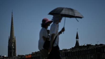 Des passants se protègent du soleil avec un parapluie à Bordeaux, le 5 juillet 2026 en Gironde, lors d'une vague de chaleur en France