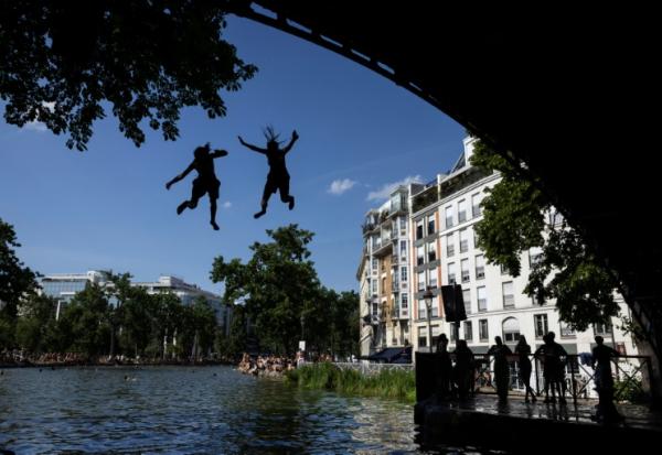 Des jeunes sautent d'un pont dans le canal Saint-Martin lors d'une vague de chaleur à Paris, le 22 juin 2026