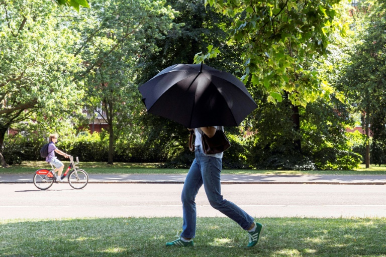 Une personne s'abrite du soleil avec un parapluie, le 22 juin 2026 à Hyde Park, à Londres