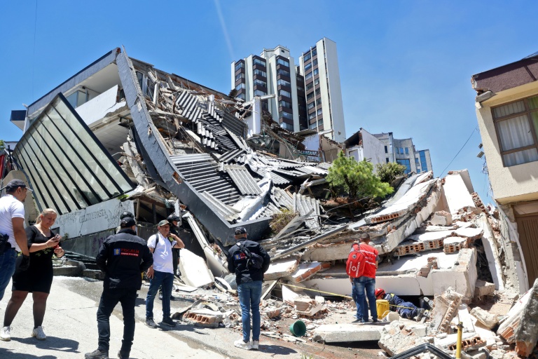 Des personnes se tiennent près d'un amas de débris après un puissant tremblement de terre à Manizales en Colombie, le 10 août 2026