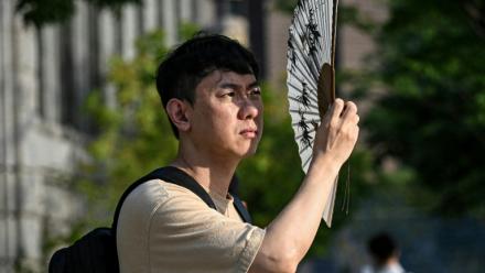 Un homme se protège du soleil avec un éventail, le 13 juillet 2026 à Séoul 