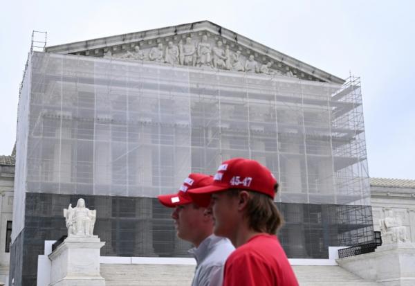 Deux hommes portant des casquettes "Make America Great Again" (MAGA, Rendre sa grandeur à l'Amérique), passent devant la Cour suprême des Etats-Unis, à Washington, le 27 juin 2025
