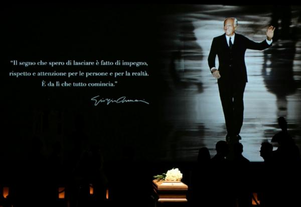 Les gens font la queue pour voir le cercueil du défunt créateur de mode italien Giorgio Armani, exposé pendant deux jours à l'Armani Theatre de Milan, tandis qu'une photo de lui est projetée sur un écran, le 6 septembre 2025