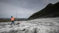 Le glaciologue Matthias Huss brandit une perche de mesure de quatre mètres de long, équivalant à la hauteur de la couche de glace ayant fondu en un an, le 24 septembre 2024 sur le glacier du Scex Rouge, en Suisse