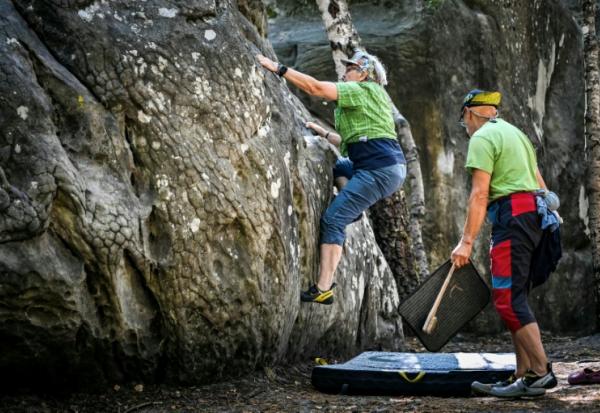 Une femme escalade un rocher à Fontainebleau, au premier jour de la réouverture au public du massif forestier partiellement dévasté par les flammes en juillet, le 22 août 2026 près de Arbonne-la-forêt, en Seine-et-Marne 