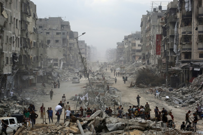 Des Palestiniens marchent au milieu de bâtiments détruits dans la ville de Gaza, le 12 octobre 2025, au troisième jour d'un cessez-le-feu entre Israël et le Hamas palestinien