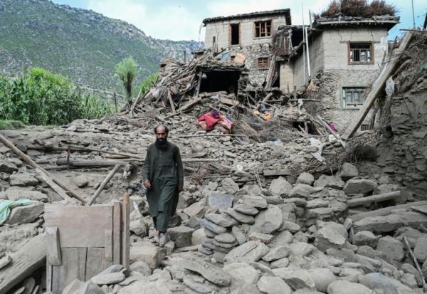 Un homme afghan passe devant une maison endommagée à la suite de tremblements de terre dans le village de Mazar Dara, situé dans le district de Nurgal, dans la province de Kunar, à l'est de l'Afghanistan, le 1er septembre 2025 après un séisme de magnitude 6,0