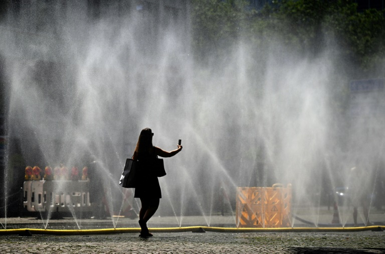 Une femme prend une photo de tuyaux d'arrosage déversant de l'eau pour apporter un peu de fraîcheur face à la chaleur estivale, à Cologne, dans l'ouest de l'Allemagne, le 25 juin 2026