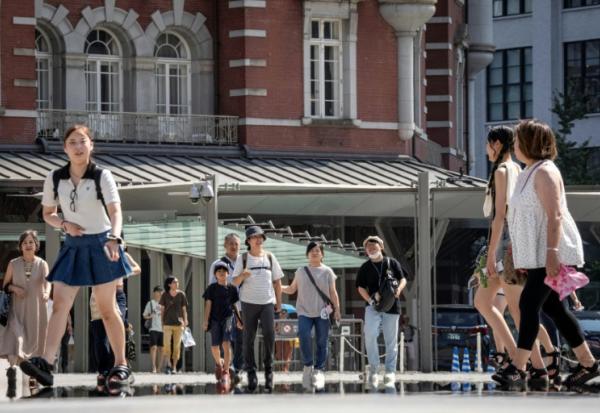 Des passants devant la gare de Tokyo un jour de chaleur le 27 août 2025