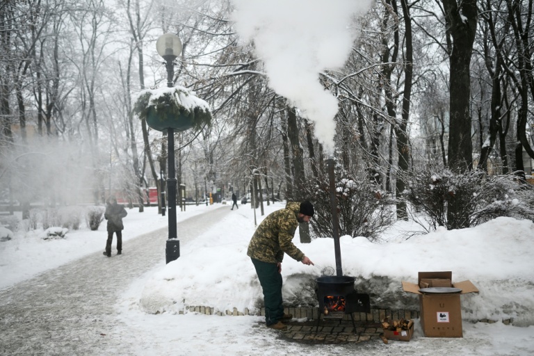 Un bénévole ukrainien cuisine un pain traditionnel d'Asie centrale dans un parc de Kiev, le 15 janvier 2026 