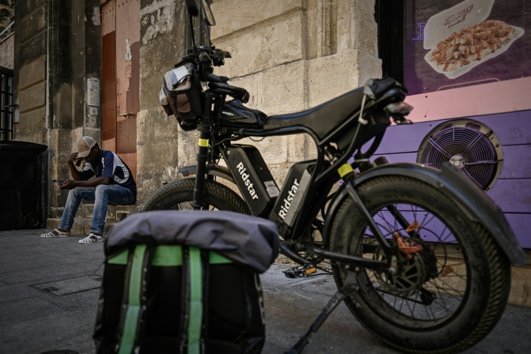 Un livreur à vélo attendant des commandes se repose pendant une vague de chaleur estivale devant un restaurant de restauration rapide à Bordeaux, le 7 juillet 2026