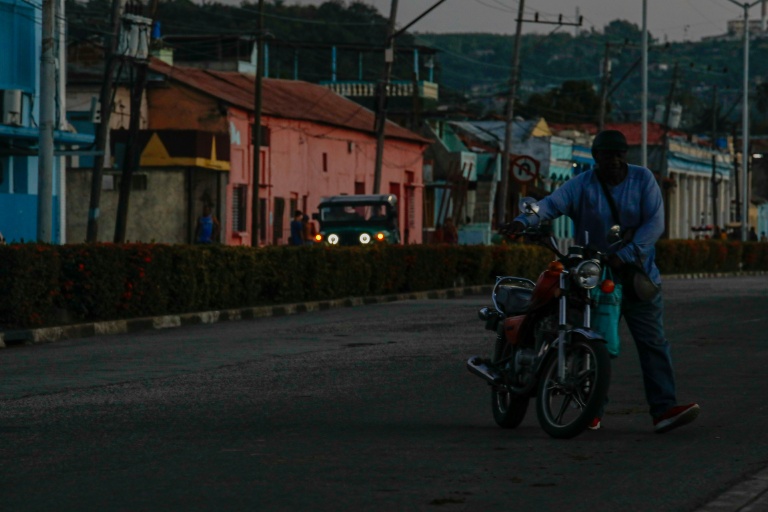 Un homme déplace une moto lors d'une panne de courant, le 14 mai 2026 à Santiago de Cuba