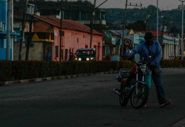 Un homme déplace une moto lors d'une panne de courant, le 14 mai 2026 à Santiago de Cuba