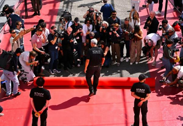 Un employé déroule le tapis rouge devant le Palais des Festivals à Cannes le 12 mai 2026