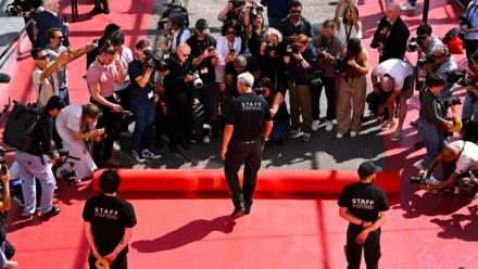 Un employé déroule le tapis rouge devant le Palais des Festivals à Cannes le 12 mai 2026