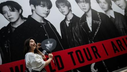 Une fan du groupe sud-coréen de K-pop BTS pose devant une affiche du groupe le 17 avril 2026 à Tokyo