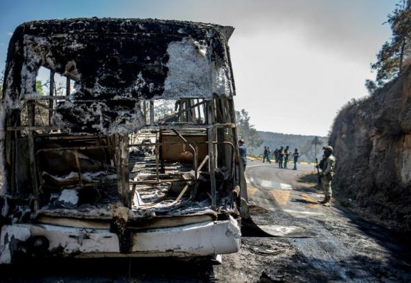Des membres de la Garde nationale et de l'armée mexicaines inspectent des véhicules suspectés d'avoir été incendiés par des membres d'un cartel sur la route entre Morelia et Patzcuaro, dans l'Etat de Michoacan, au Mexique, le 22 février 2026