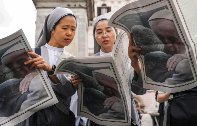 Des religieuses lisent le journal Osservatore Romano avec le pape François en dernière page près de la basilique Sainte-Marie-Majeure, un jour avant les funérailles du défunt pape, à Rome, le 25 avril 2025