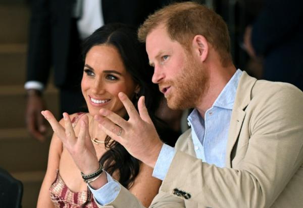 Le prince Harry (à droite), duc de Sussex, s'entretient avec son épouse Meghan Markle alors qu'ils assistent à un spectacle lors d'une visite au Centre national des arts de Bogota, le 15 août 2024.